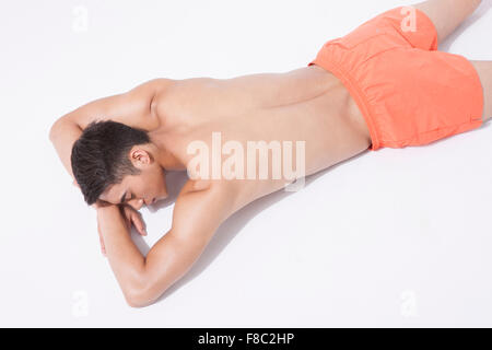 High angle de l'homme musclé en natation de pantalon reposant sa tête sur ses mains, les yeux fermés Banque D'Images