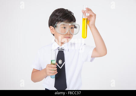 Garçon de l'école élémentaire portant des lunettes expérimentales et holding test tube Banque D'Images