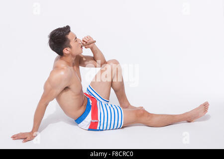 Pantalon homme musclé en natation se penchant en arrière sur le sol et le tabagisme Banque D'Images