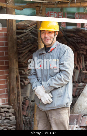 Construction Worker posing et regardant la caméra avec un casque jaune à Shanghai Banque D'Images