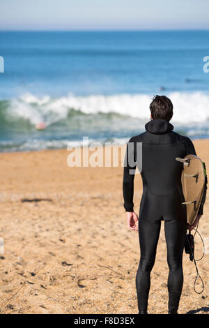 Jeune internaute homme debout sur une plage, et portant son voile Banque D'Images