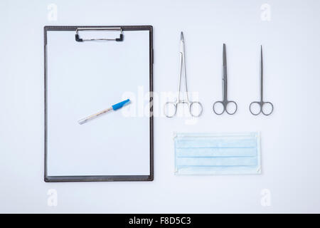 L'espace de copie d'un dossier médical avec un stylo à côté de différents types de ciseaux et d'un masque Banque D'Images