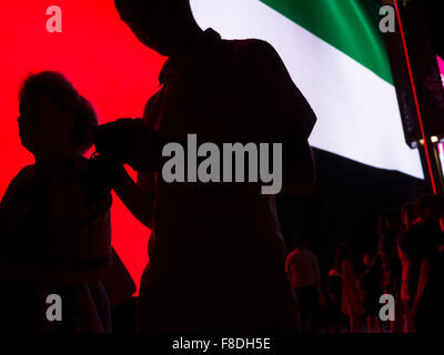 Silhouette de personnes en face d'eau géant (Emirats Arabes Unis) drapeau dans le centre commercial de Dubaï. Banque D'Images