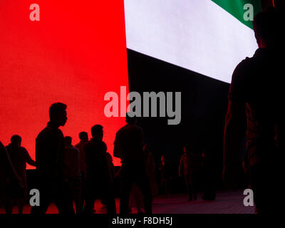 Silhouette de personnes en face d'eau géant (Emirats Arabes Unis) drapeau dans le centre commercial de Dubaï. Banque D'Images