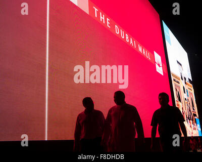 Silhouette de personnes en face de l'écran numérique géant de la publicité commerciale dans le centre commercial de Dubaï, Dubaï, Emirats Arabes Unis. Banque D'Images