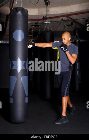 L'homme contre le sac de boxe au club Banque D'Images