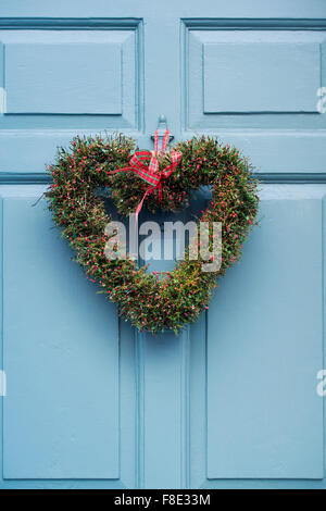 Couronne de Noël en forme de coeur sur une porte en bois bleu pâle Banque D'Images