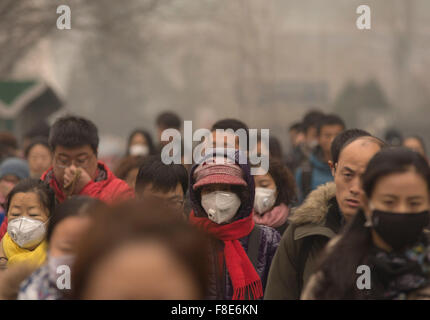 Les gens et les navetteurs portent un masque facial sur leur chemin vers le travail, bravant ainsi la lourde pollution de l'air dans la capitale chinoise alors que les niveaux ont grimpé à plus de 20 fois les niveaux de sécurité, ce qui a donné lieu à une alerte rouge pour tout Pékin. © Olli Geibel Banque D'Images