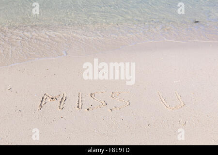 Mlle vous écrit dans le sable humide sur une plage tropicale Banque D'Images