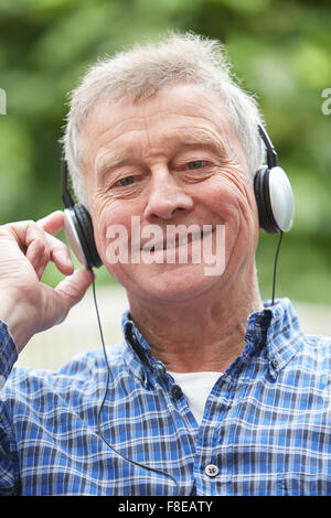 Senior Woman Relaxing Listening to Music On Headphones In Garden Banque D'Images