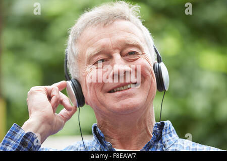 Senior Woman Relaxing Listening to Music On Headphones In Garden Banque D'Images