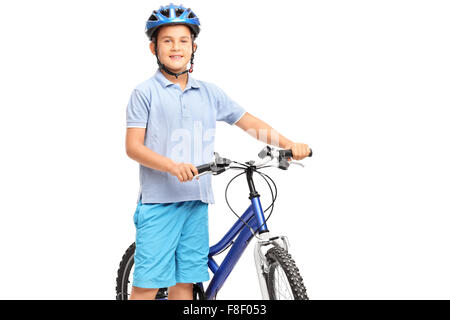 Petit garçon avec un casque bleu qui pose à côté de son vélo et regardant la caméra isolé sur fond blanc Banque D'Images