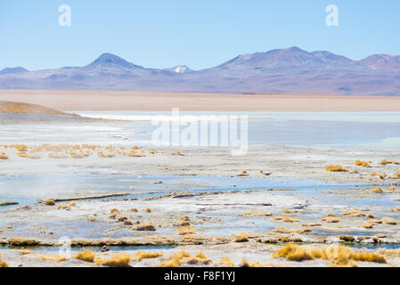 Les étangs d'eau chaude géothermique en région des hauts plateaux andins de Bolivie. Frozen salt lake, de montagnes lointaines et stérile vol Banque D'Images