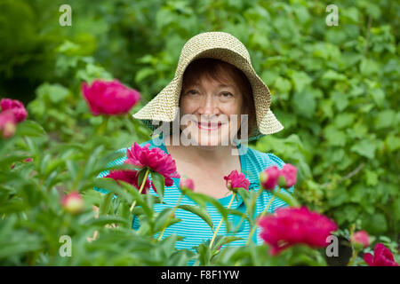 Happy female gardener dans le jardin des plantes à fleurs Banque D'Images