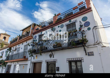 Rangée de maisons blanches l'espagnol à Grenade avec balcons pleins de pots de géranium et autres fleurs et des assiettes en céramique sur le mur Banque D'Images