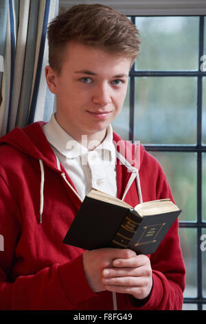 Teenage Boy Reading Bible à la maison Banque D'Images