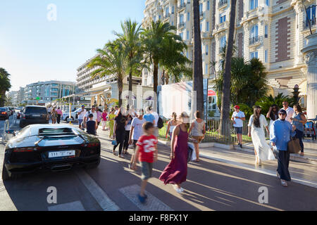 Les gens qui marchent dans un après-midi d'été le long du boulevard de la Croisette à Cannes près de Intercontinental Carlton hôtel et voiture de luxe Banque D'Images