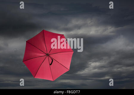 Parapluie rouge soufflant en tempête Banque D'Images