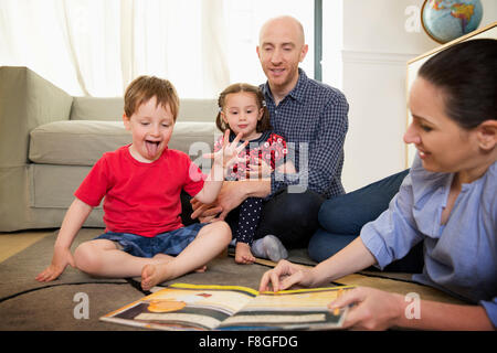 Livre de lecture en famille sur le plancher dans la salle de séjour Banque D'Images