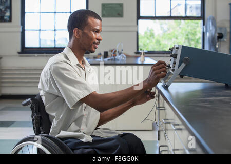 African American paraplegic student performing experiment in science classroom Banque D'Images