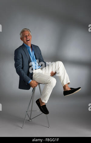 Caucasian businessman laughing on stool Banque D'Images