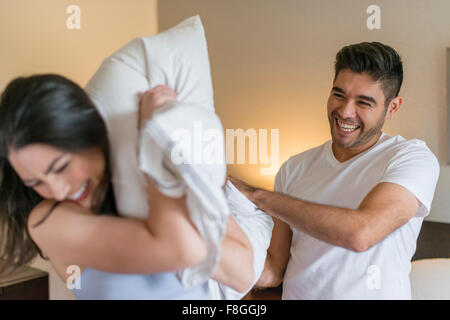 Hispanic couple having pillow fight Banque D'Images