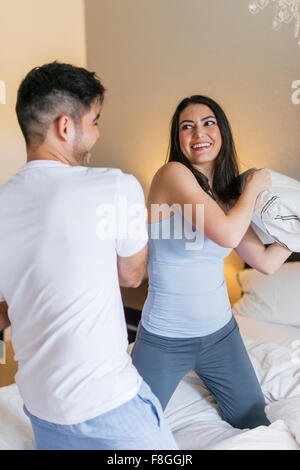 Hispanic couple having pillow fight Banque D'Images