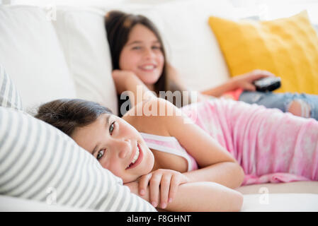 Caucasian twin sisters laying on sofa Banque D'Images