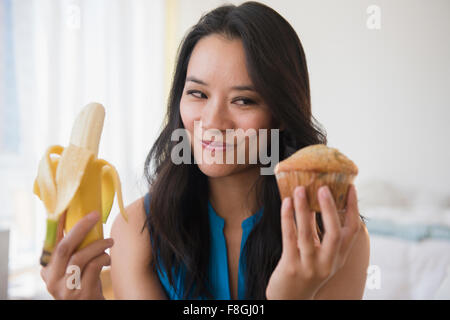 Femme chinoise choisir entre muffin banane et Banque D'Images