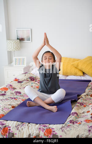 Girl practicing yoga on bed Banque D'Images