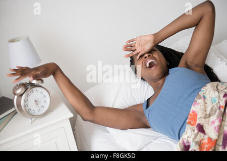 Femme noire le réveil avec alarme réveil Banque D'Images