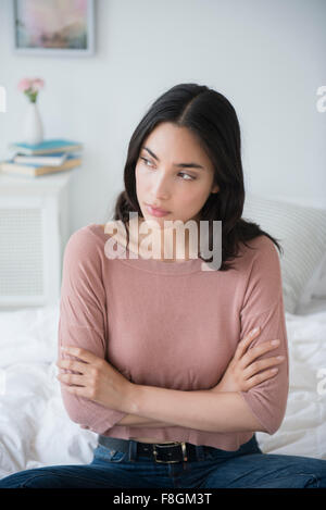 Frustrés Hispanic woman sitting on bed Banque D'Images