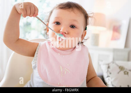 Mixed Race baby girl eating yoghurt Banque D'Images