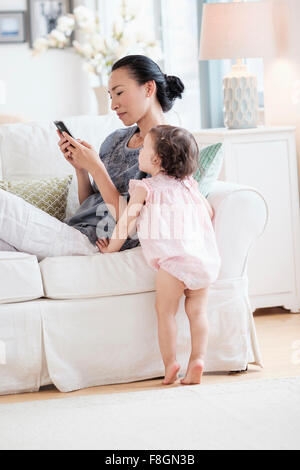 Mère et fille bébé using cell phone Banque D'Images