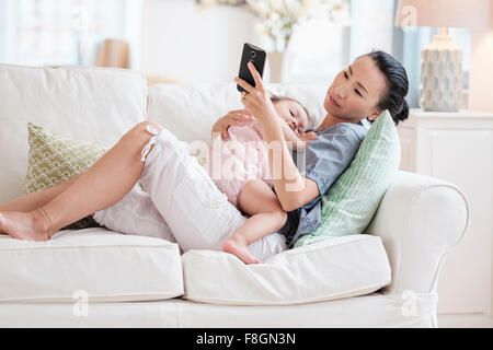 Mère et fille bébé using cell phone Banque D'Images