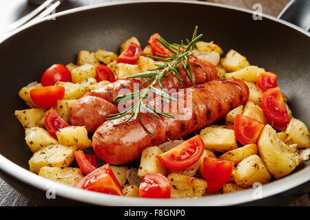 Saucisses grillées dans le moule sur une table en bois entourée par des ingrédients Banque D'Images