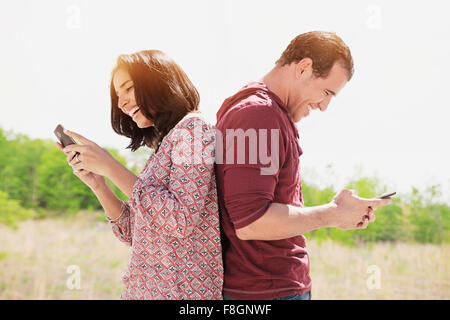 Couple l'utilisation de téléphones cellulaires en plein air Banque D'Images