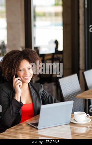 Mixed Race Woman talking on cell phone in cafe Banque D'Images