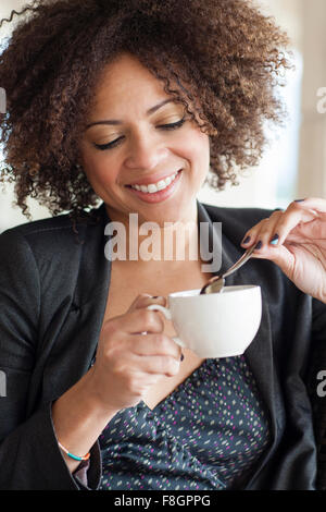 Mixed Race businesswoman drinking cup of coffee Banque D'Images