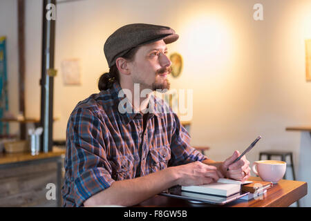 Caucasian student doing Homework in cafe Banque D'Images