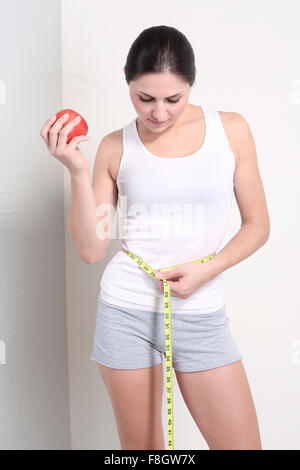 Caucasian woman holding apple measuring waist Banque D'Images