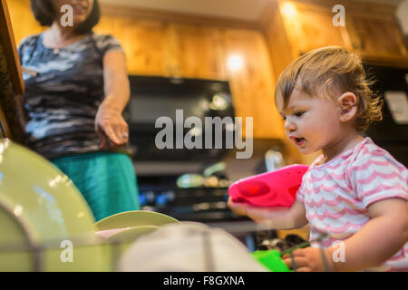 Baby Girl aider charge mère lave-vaisselle Banque D'Images