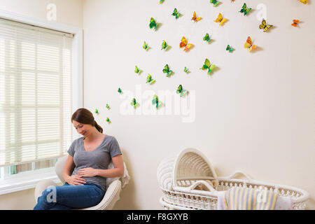 Young pregnant woman sitting in nursery Banque D'Images