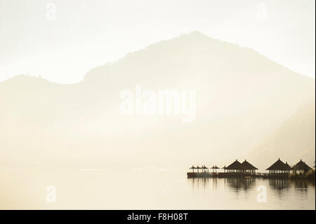 Abris se reflétant dans le lac distant encore sous des montagnes Banque D'Images