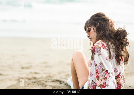Caucasian woman sitting in sand on beach Banque D'Images