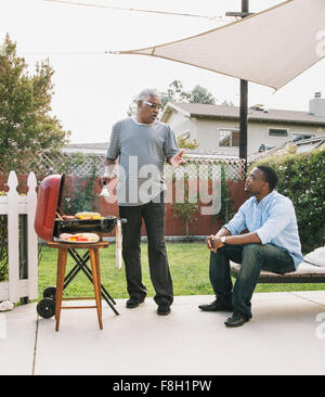 African American father and son talking at barbecue Banque D'Images