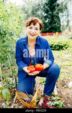 Caucasian woman holding tomatoes in garden Banque D'Images