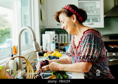 Laver les légumes Caucasian woman in kitchen Banque D'Images