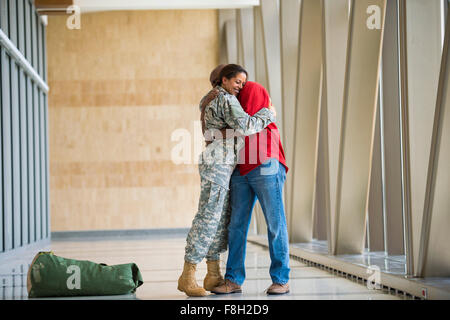 African American soldier hugging husband in airport Banque D'Images