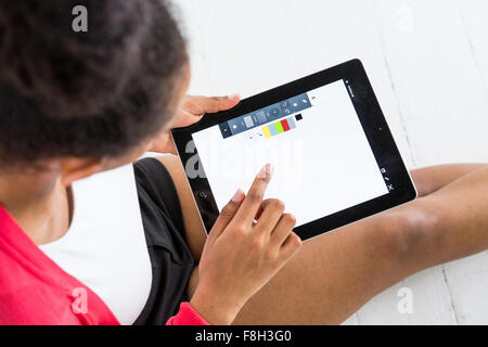 Une jeune femme afro-américaine à l'aide d'un comprimé ou de l'iPad dans un paramètre de type studio Banque D'Images